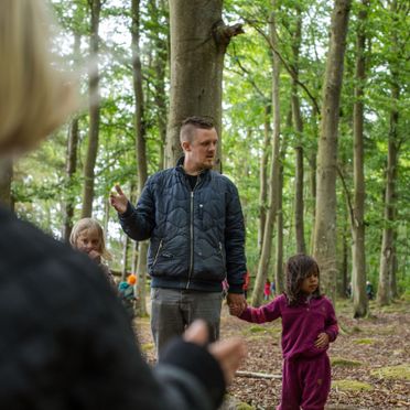 Skovgruppebørn i Lille-Gryn leger med de voksne i skoven ved Svaneke på Bornholm.